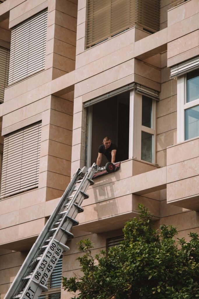 A man standing on a telescopic ladder at a residential building in Valencia, Spain.